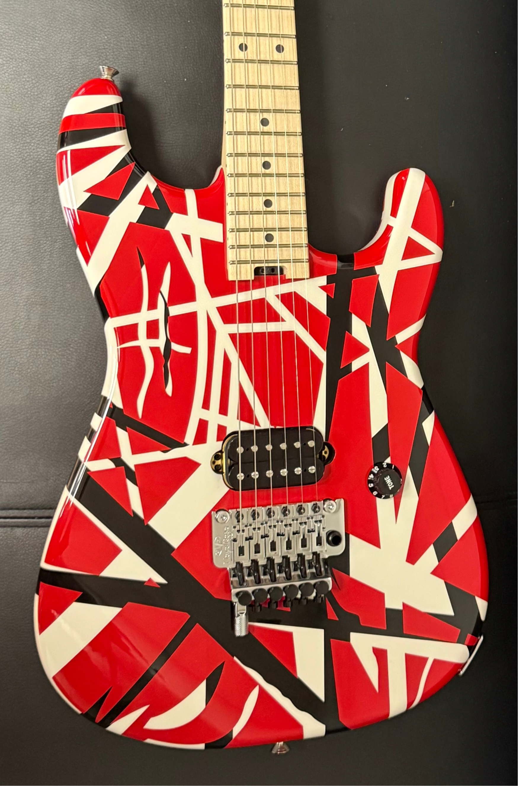 Guitar with red, black, and white striped design on a dark background