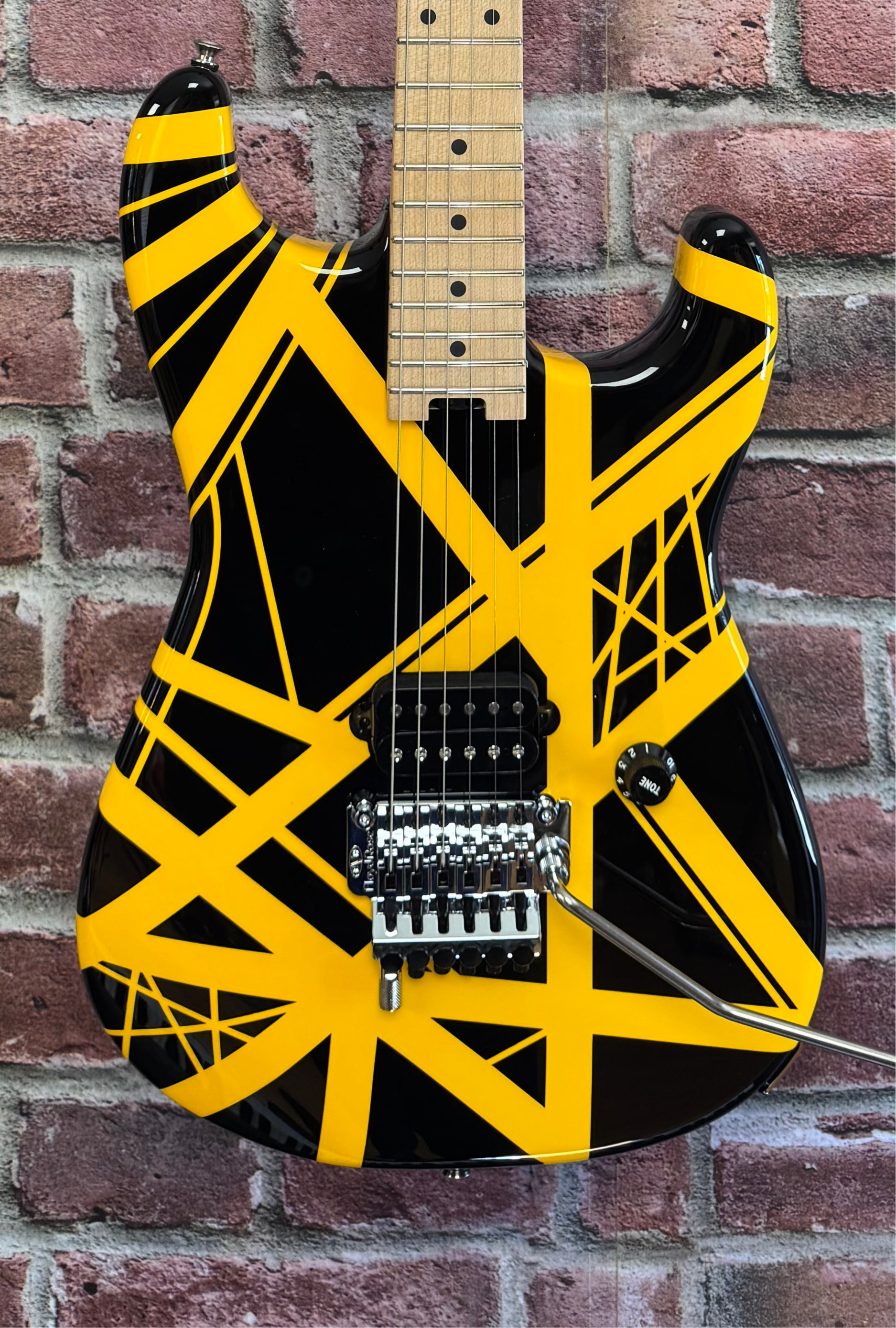 Black and yellow electric guitar against a brick wall