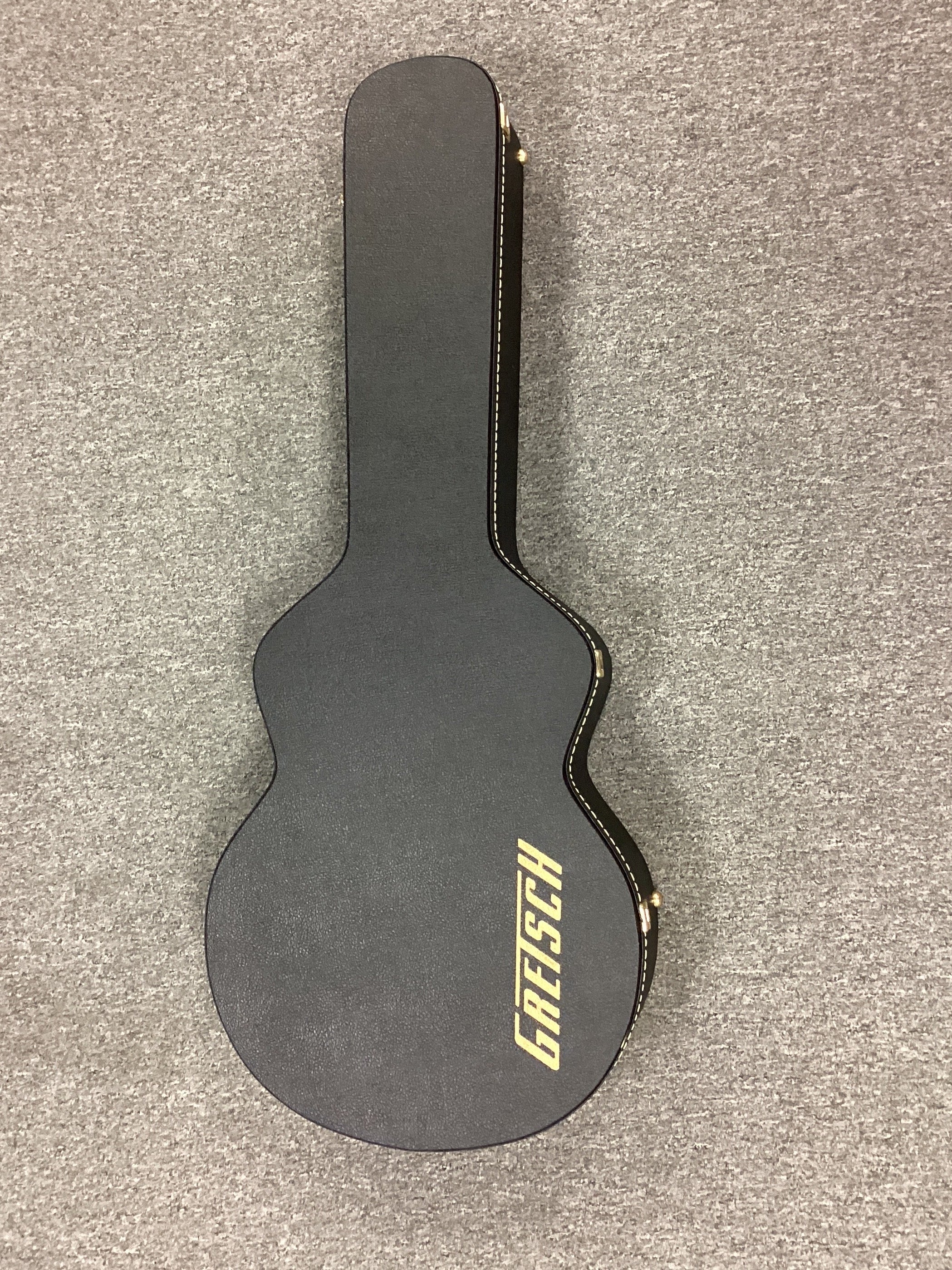 Image of Black Gretsch guitar case on a gray surface