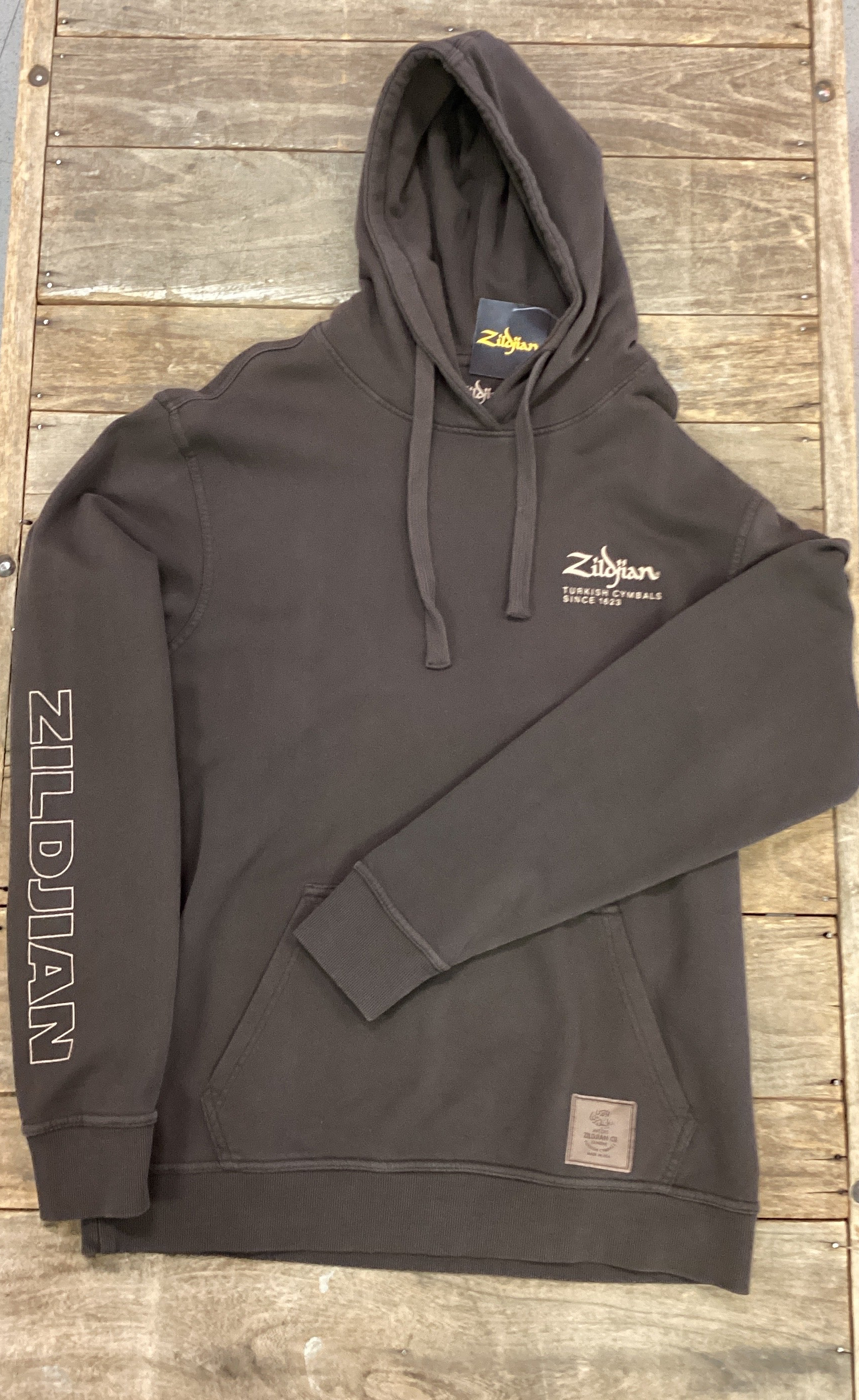 Image of Dark gray hoodie with Zildjian logo on a wooden surface