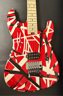 Image of Guitar with red, black, and white striped design on a dark background