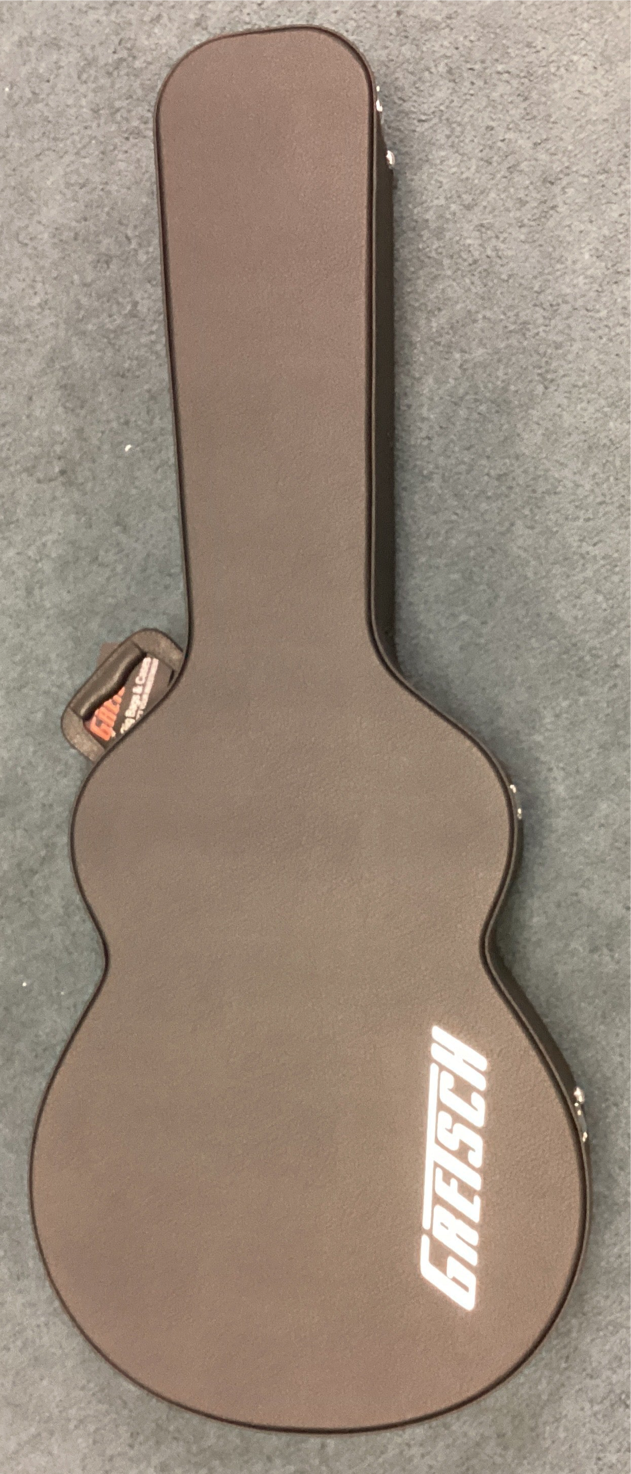 Brown Gretsch guitar case on a gray surface
