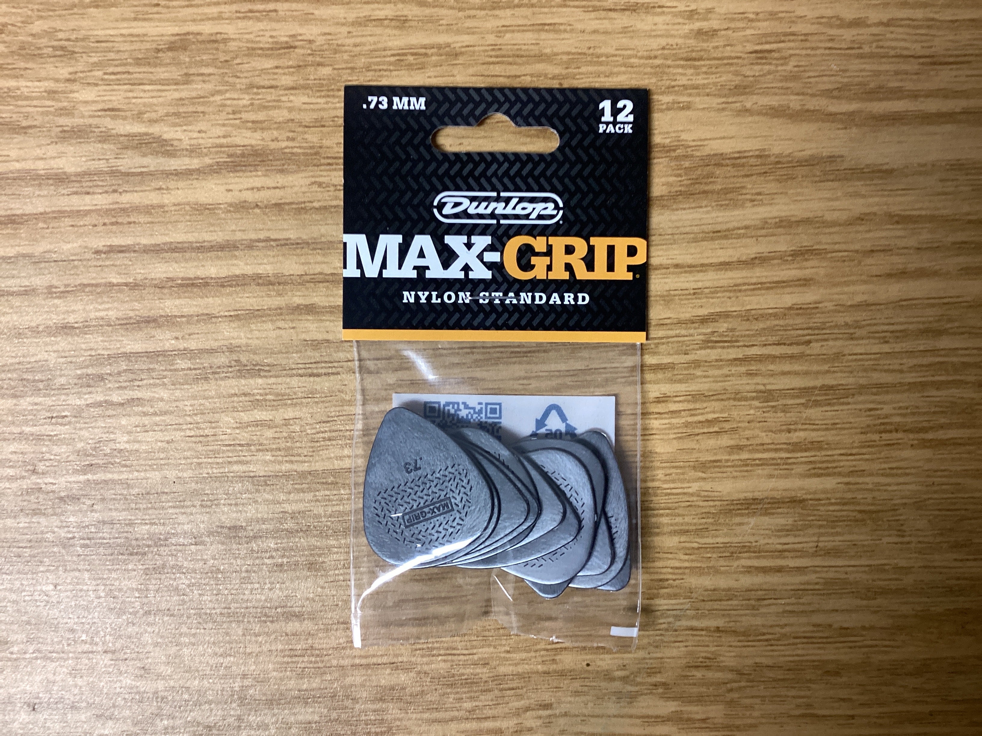 Image of Pack of Dunlop Max-Grip guitar picks on a wooden surface