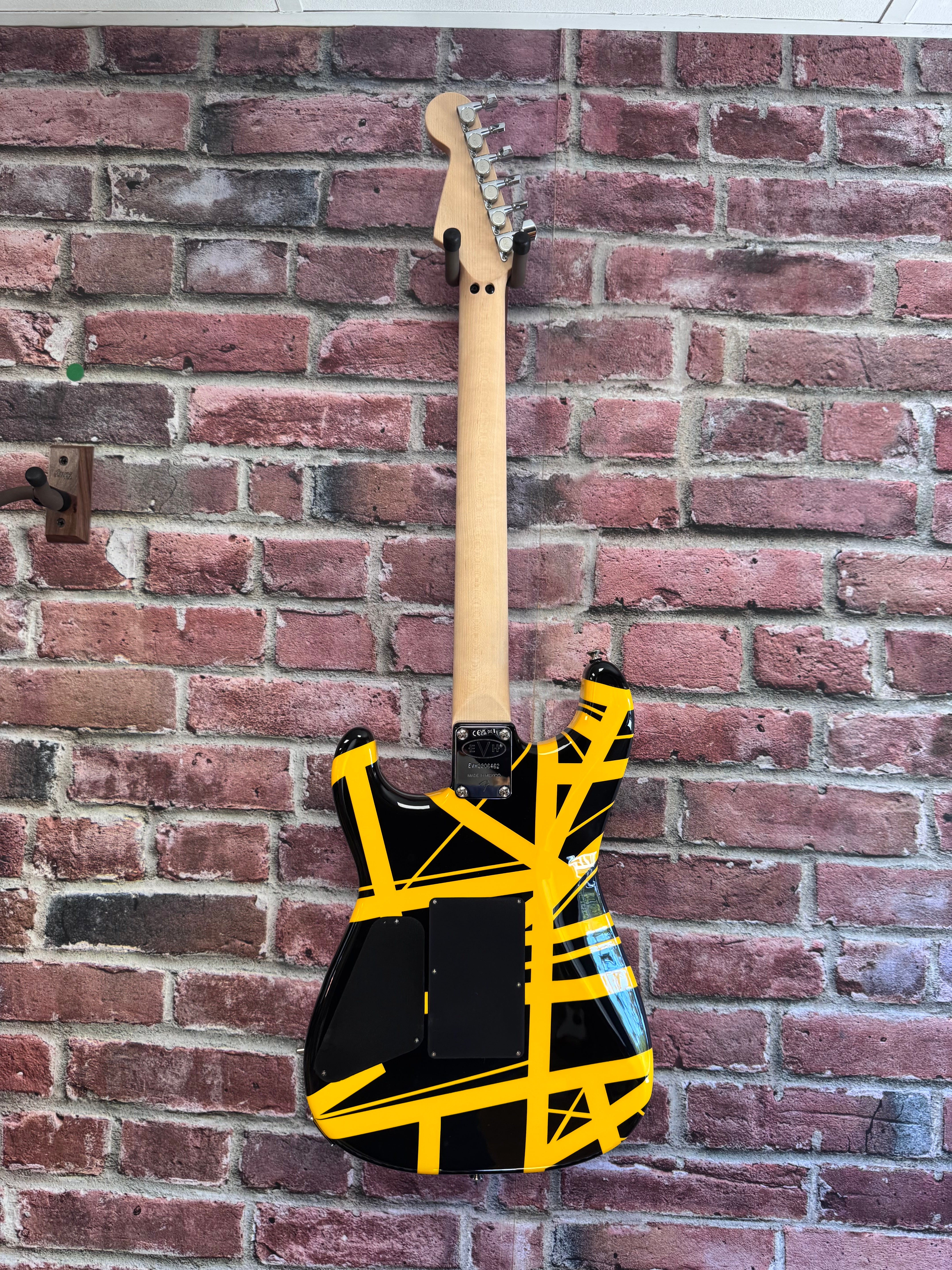 Image of Guitar with black and yellow design leaning against a brick wall