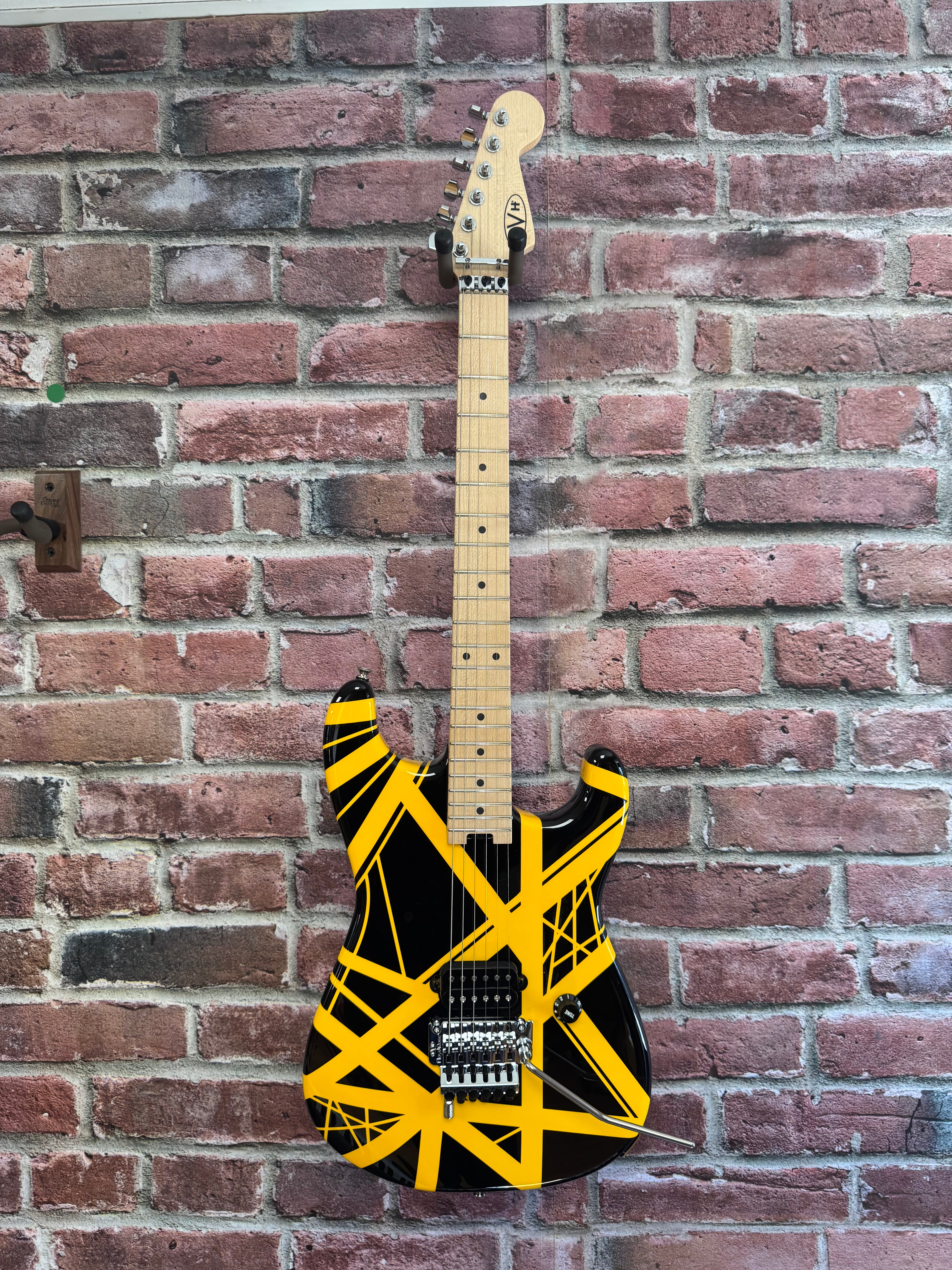 Image of Electric guitar with black and yellow design against a brick wall