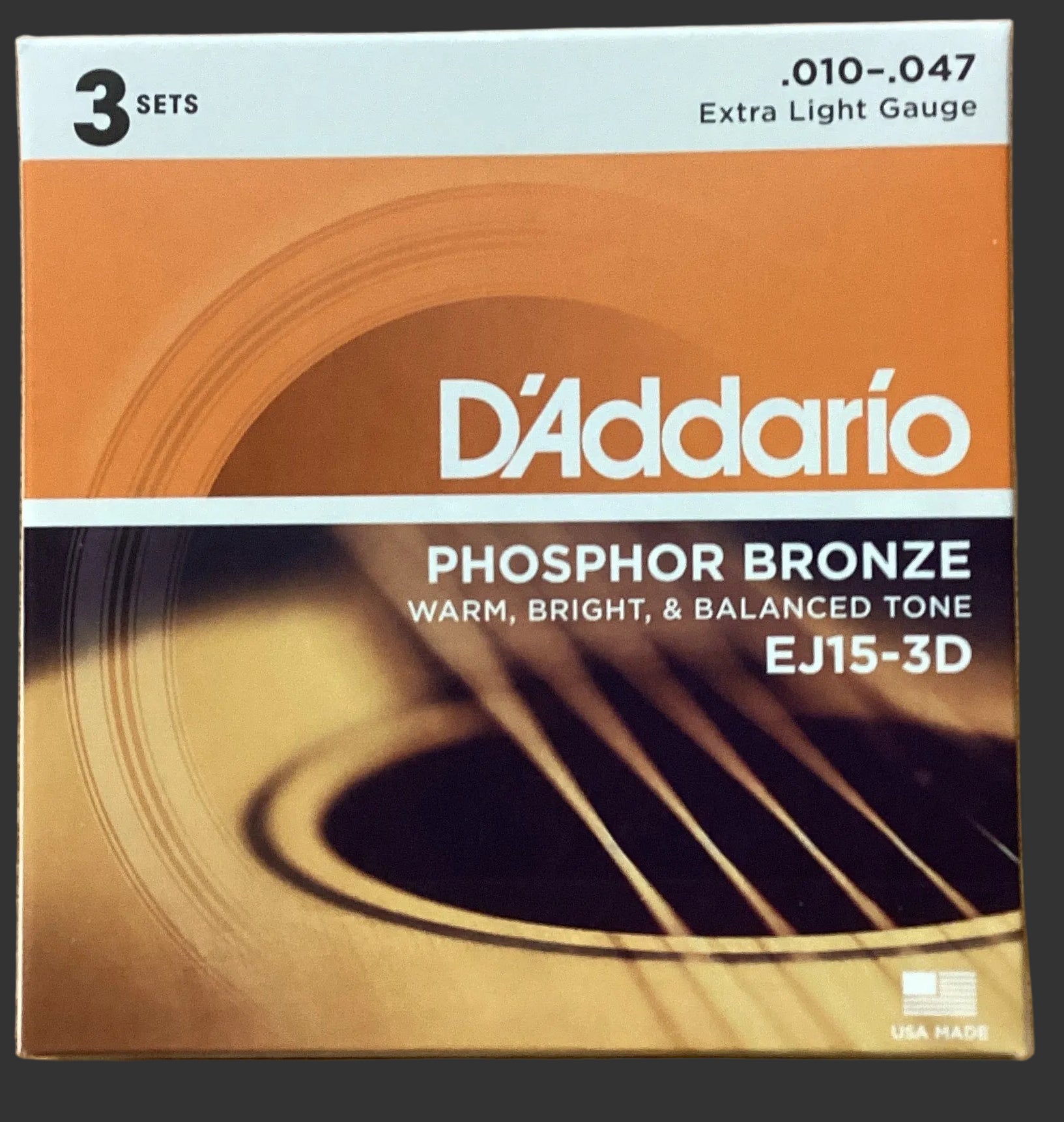 Image of D'Addario phosphor bronze acoustic guitar strings packaging on a wooden surface