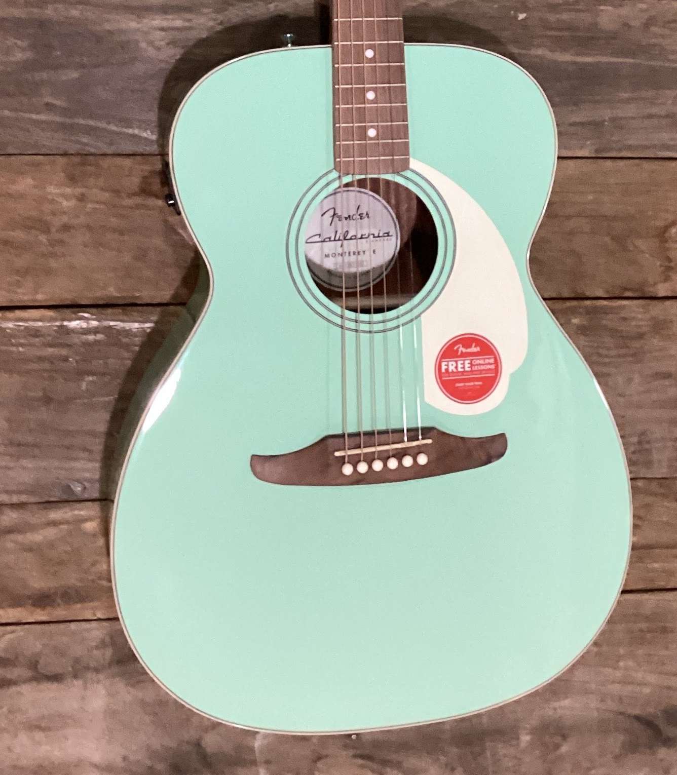 Image of Mint green acoustic guitar with Fender logo on a wooden background