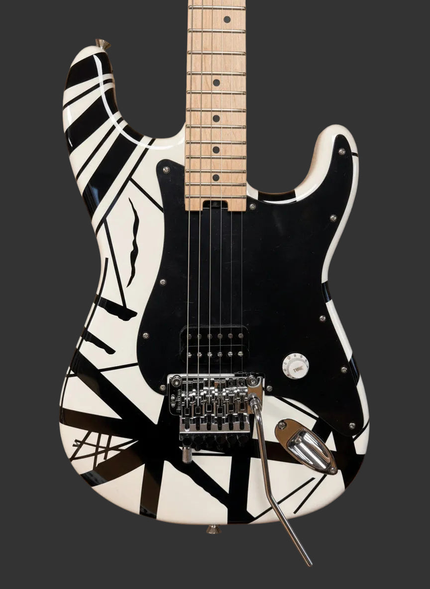 Image of Black and white electric guitar against a brick wall